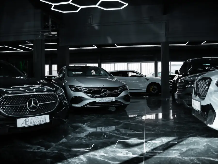 Silberner Mercedes EQ neben weiteren Fahrzeugen unter der Hexagon-Beleuchtung