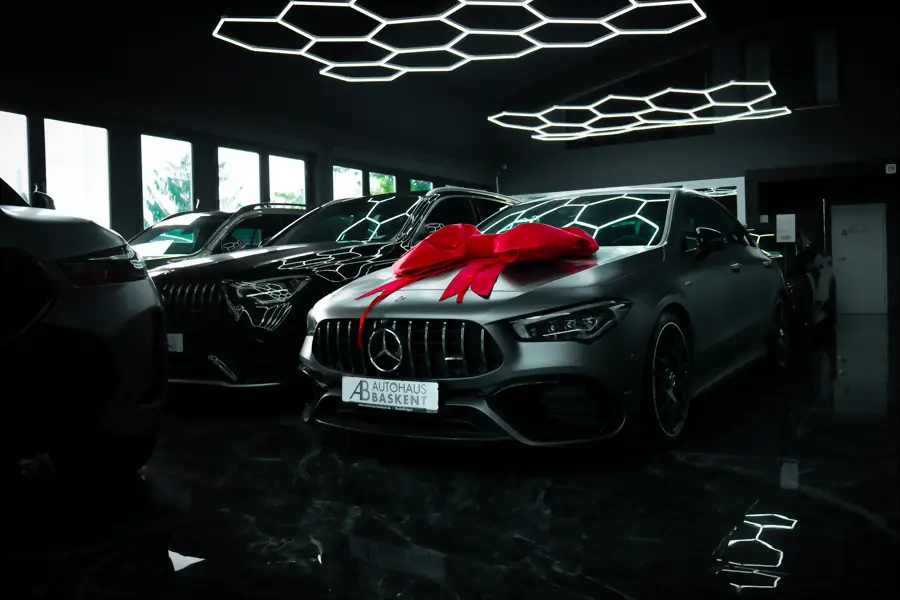 Mercedes-AMG mit roter Übergabe-Schleife in der Halle, dahinter weitere Fahrzeuge